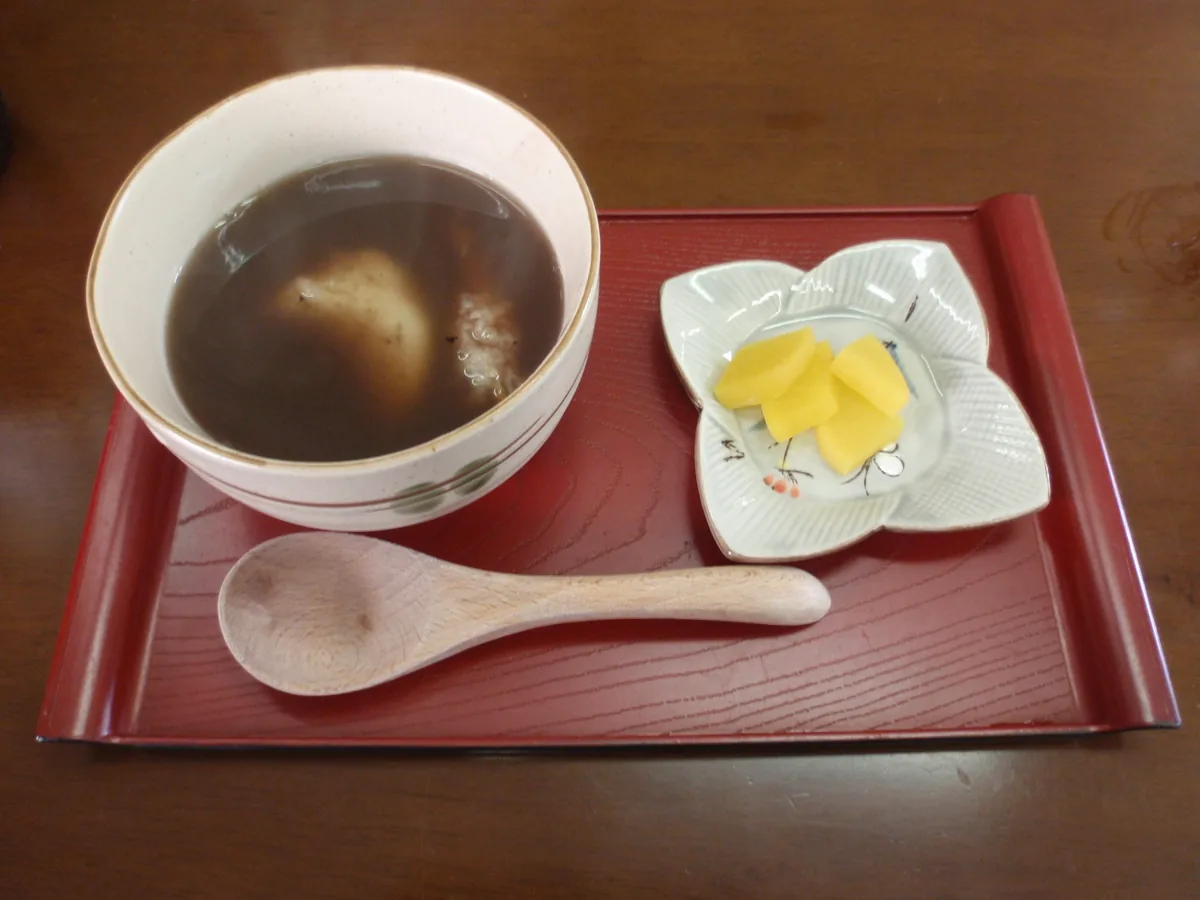 Izumo zenzai with rice cake in a bowl, served with yellow pickles on a red tray