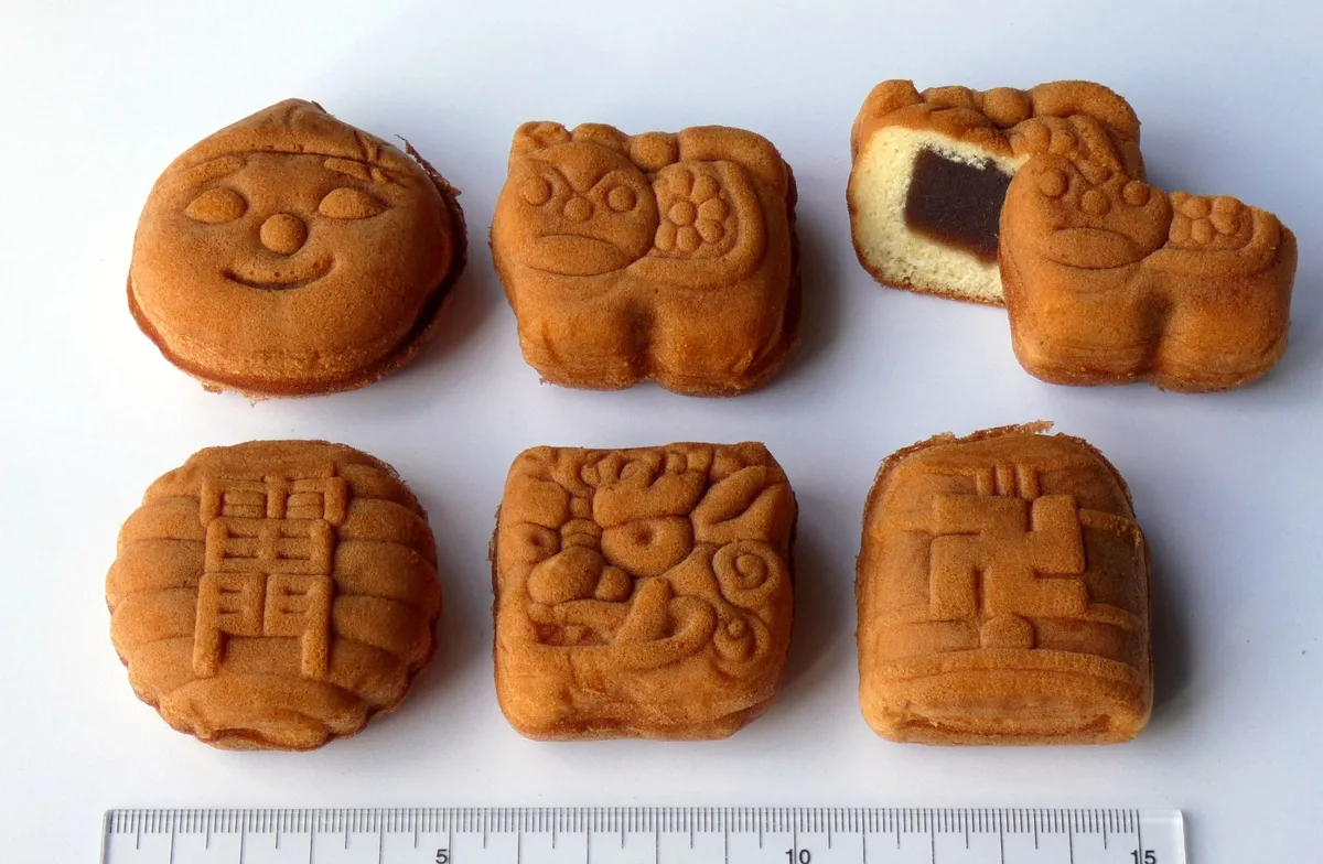 いろいろな形の人形焼を並べた写真。下に定規が写っている