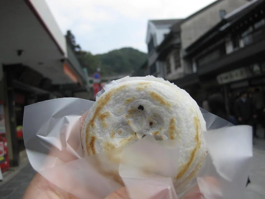 A freshly grilled umegae mochi held up on the approach to Dazaifu Tenmangu